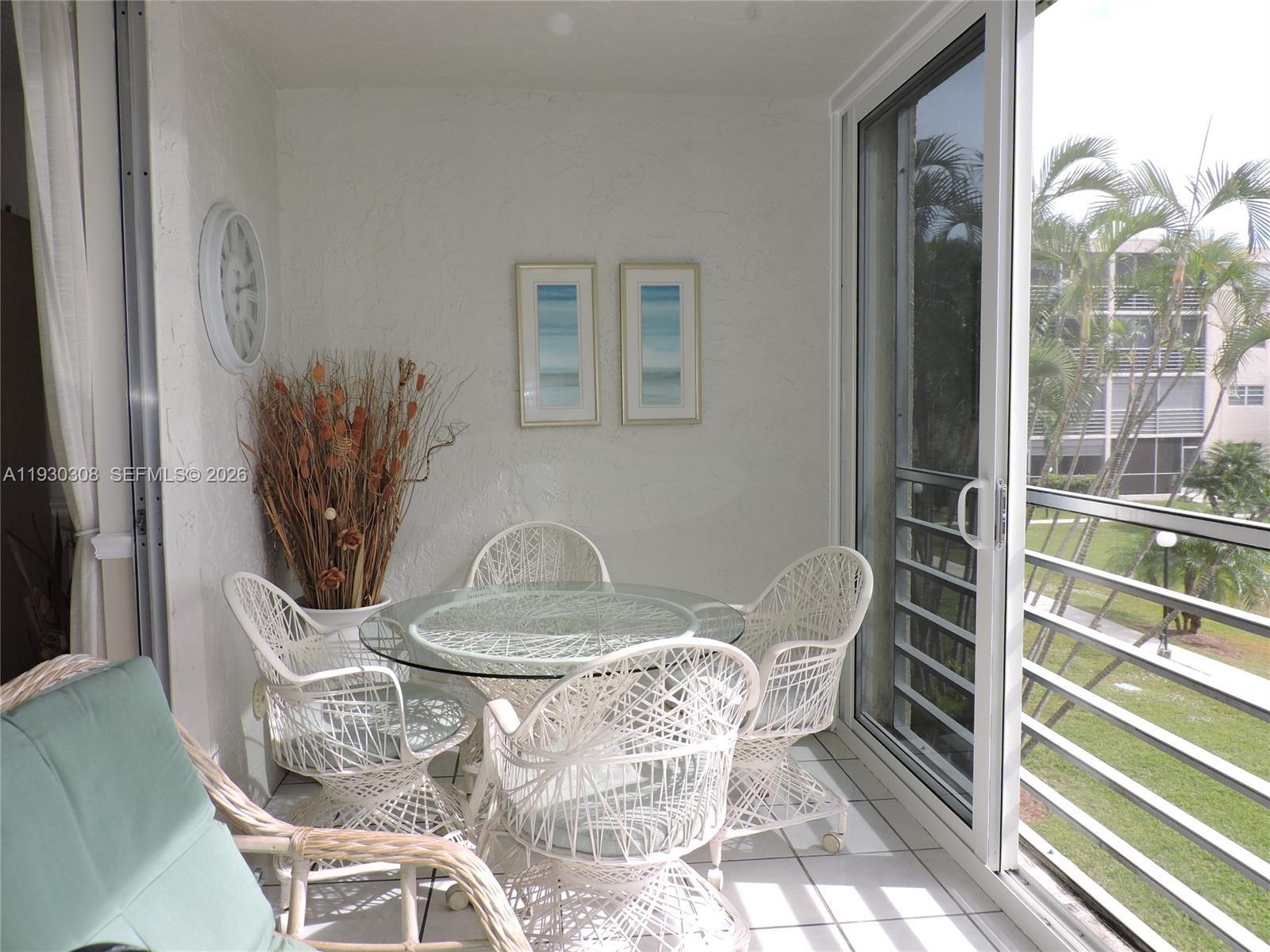 A sunroom features a glass-topped table with four white wicker chairs and tile flooring — 324 SE 10th St # 207, Dania Beach FL 33004, DANIA BEACH, FL