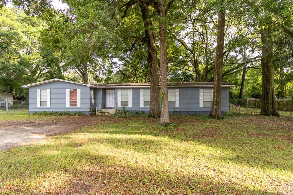A single-story blue house with a white front door sits on a grassy lot — 14215 NW 142ND PLACE, ALACHUA, FL