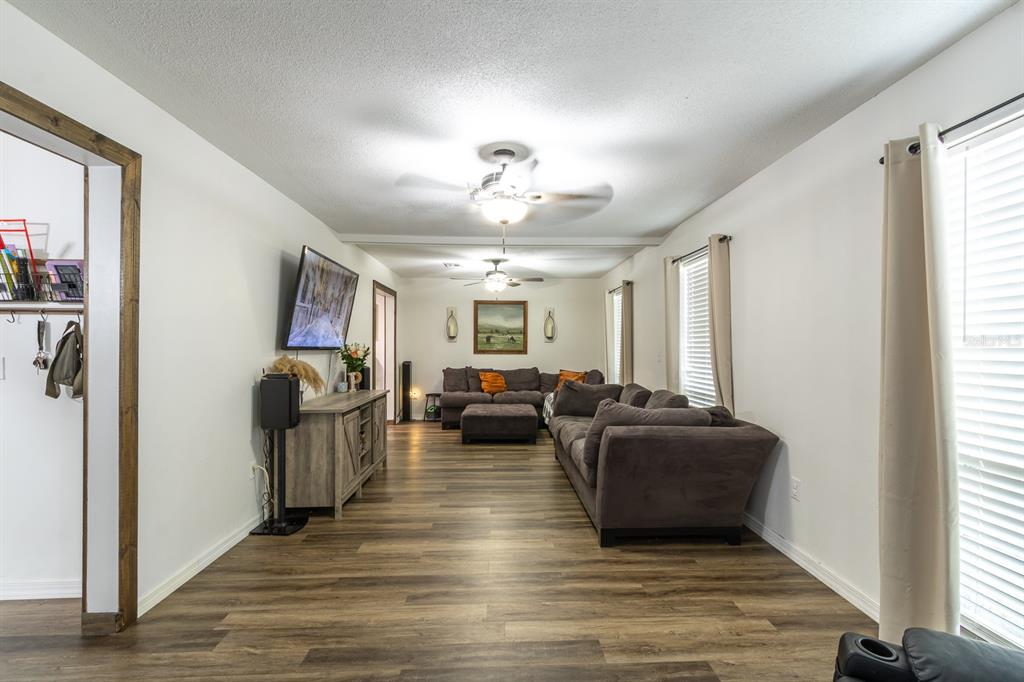 A living room features wood-look flooring, two gray sofas, and a ceiling fan — 14215 NW 142ND PLACE, ALACHUA, FL