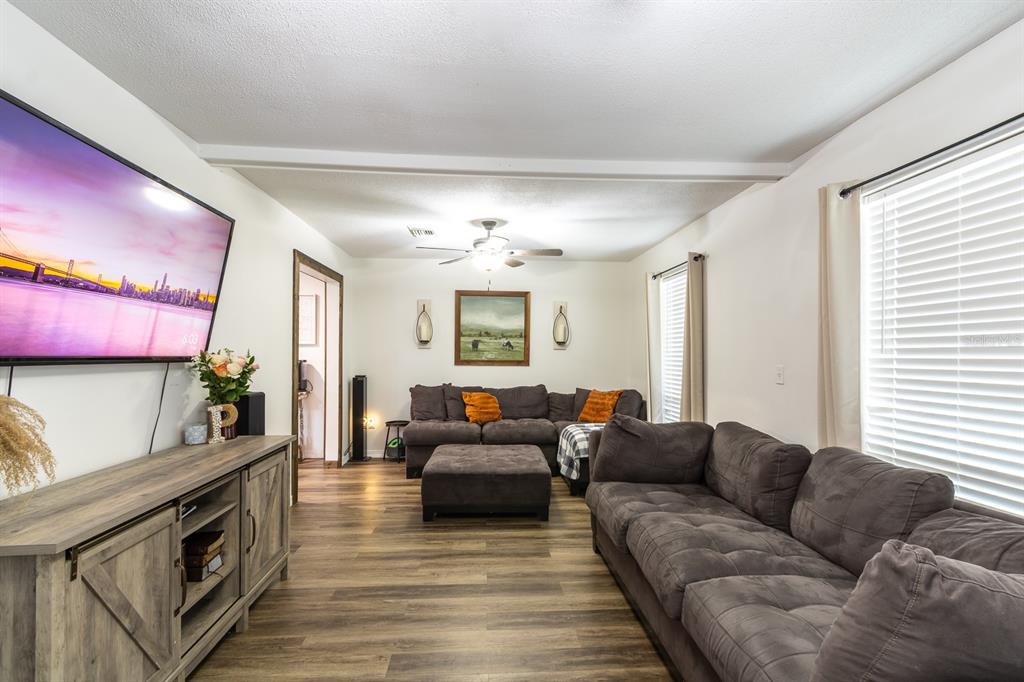 A living room features a large sectional sofa, a television, and wood-look flooring — 14215 NW 142ND PLACE, ALACHUA, FL