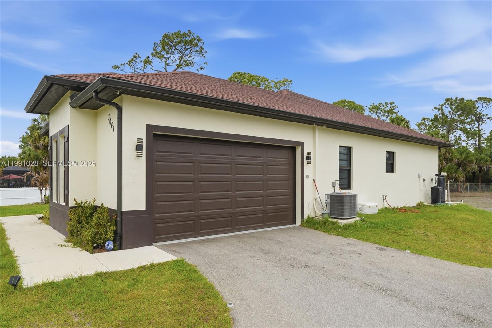 The exterior of a single-story house features a two-car garage and a paved driveway — 3043 18, Naples FL 34120, NAPLES, FL