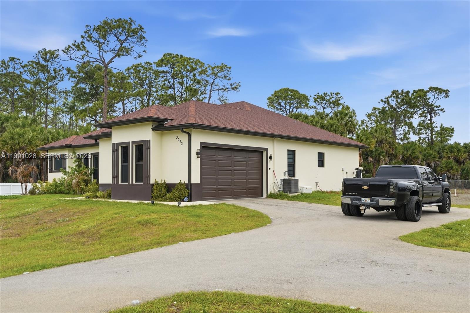 A single-story house with a brown roof, beige stucco walls, and a two-car garage — 3043 18, Naples FL 34120, NAPLES, FL