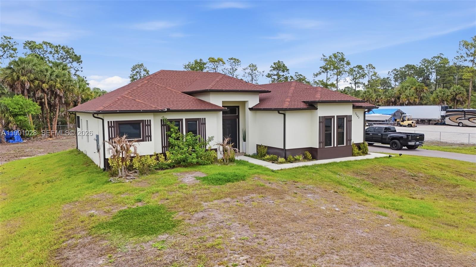 A single-story house with a brown roof and cream-colored exterior sits on a grassy lot — 3043 18, Naples FL 34120, NAPLES, FL