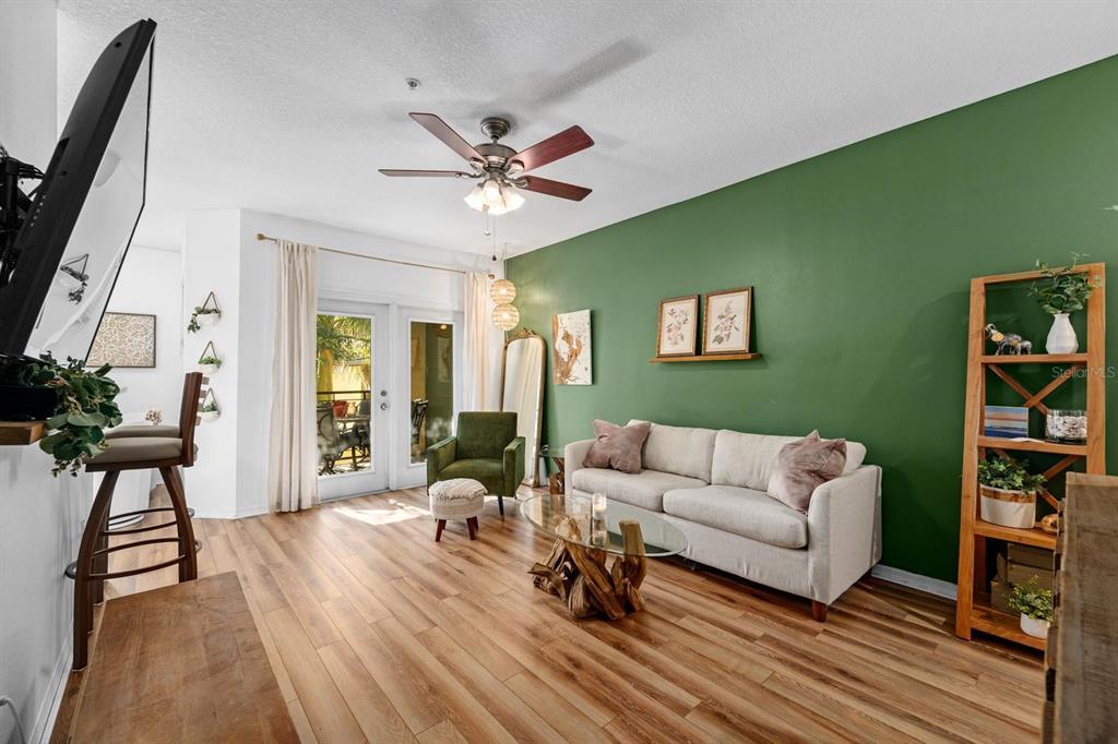A living room features a green accent wall, light wood flooring, and a beige sofa — 2010 E PALM AVENUE UNIT 14317, TAMPA, FL