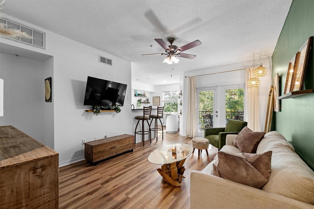 A living room features wood-look flooring, a mounted television, a sofa, and a ceiling fan — 2010 E PALM AVENUE UNIT 14317, TAMPA, FL