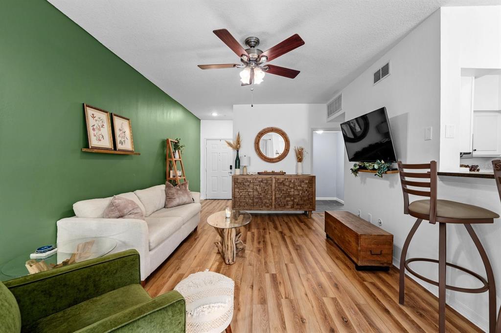 A living room features a green accent wall, wood-look flooring, and a ceiling fan — 2010 E PALM AVENUE UNIT 14317, TAMPA, FL