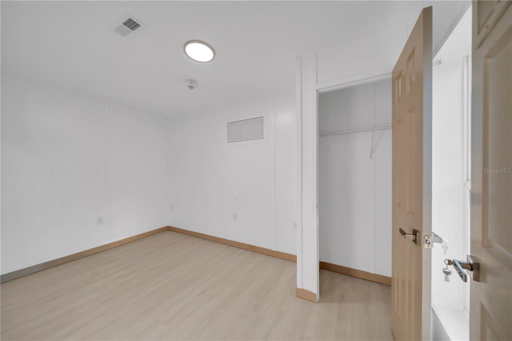 A bedroom with white walls, light wood-look flooring, a closet, and a recessed ceiling light — 7483 DANVERS CIRCLE, PORT CHARLOTTE, FL