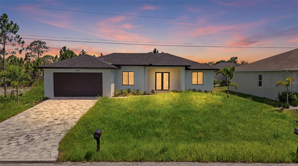 A single-story house with a paved driveway, a dark garage door, and a grassy lawn — 14041 NEWSON LANE, PORT CHARLOTTE, FL