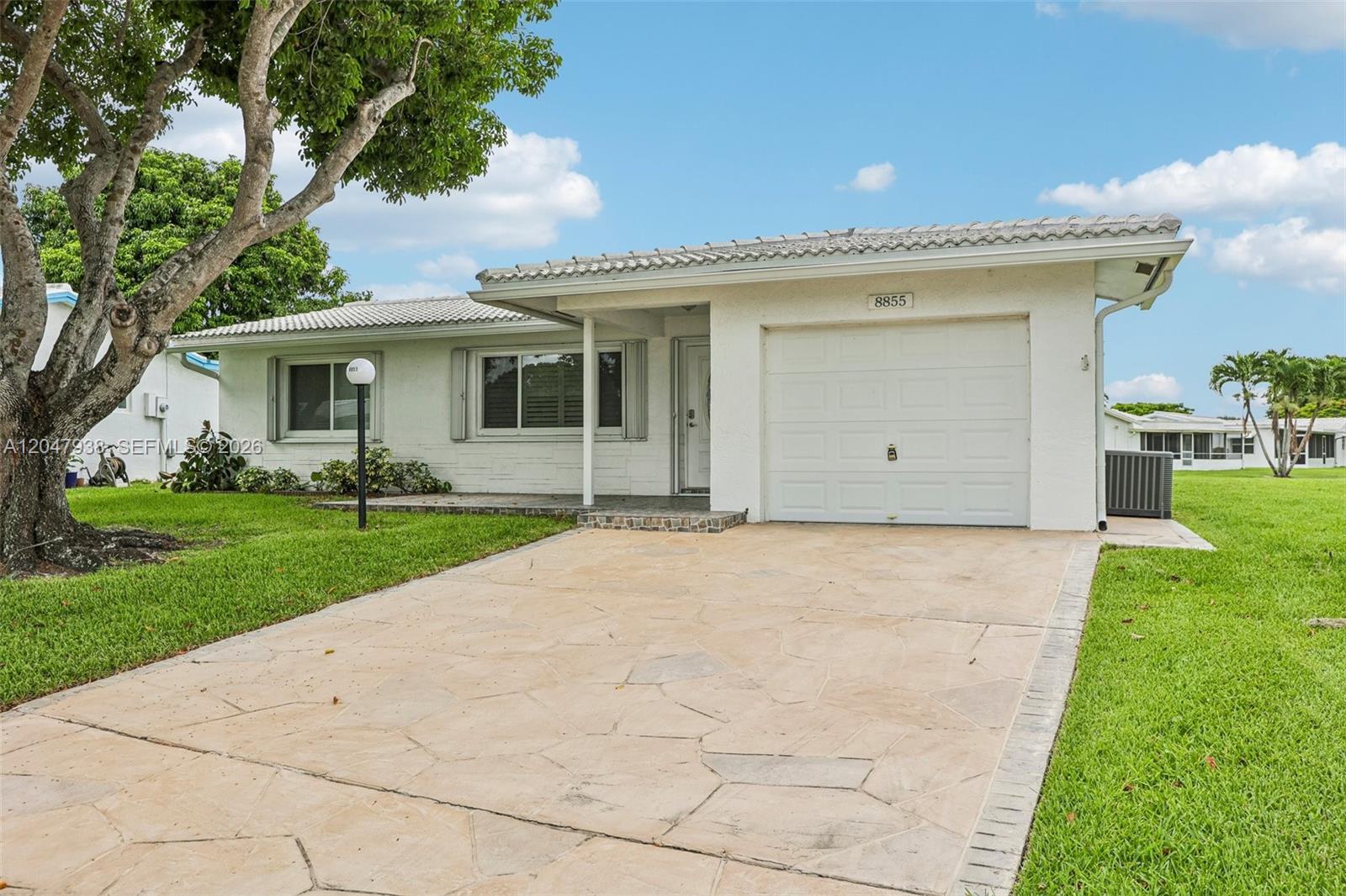 A single-story house with a white exterior, tiled roof, and a stone-paved driveway — 8855 NW 10th Pl, Plantation FL 33322, PLANTATION, FL