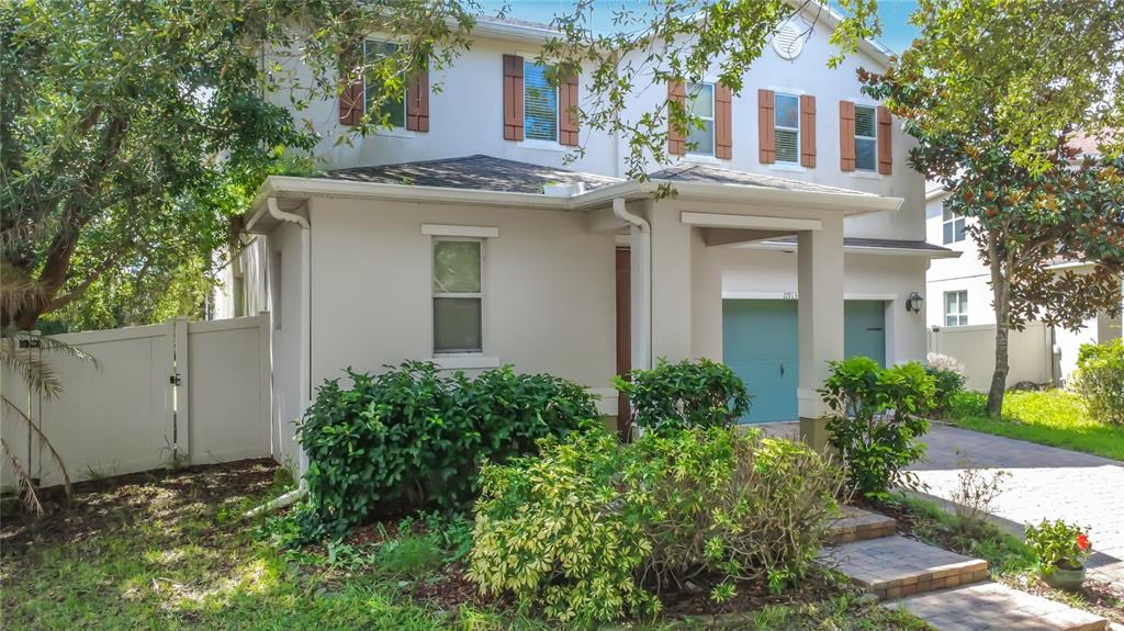 A two-story suburban house with a light-colored exterior, green garage doors, and landscaped front yard — 11913 VERRAZANO DRIVE, ORLANDO, FL
