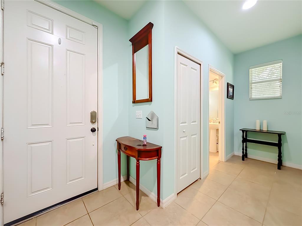 An entryway features light blue walls, tile flooring, a white door, and two wooden tables — 11913 VERRAZANO DRIVE, ORLANDO, FL
