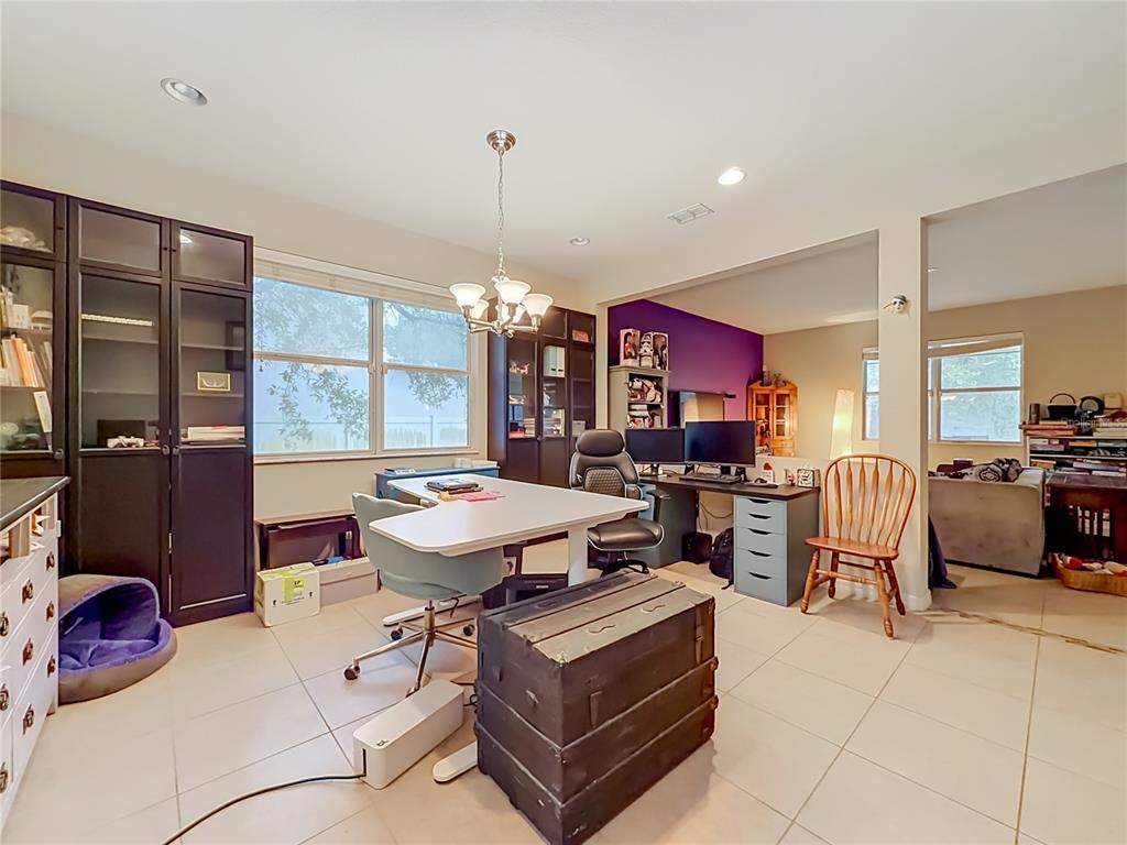 A home office features a white desk, dark storage cabinets, and a purple accent wall — 11913 VERRAZANO DRIVE, ORLANDO, FL