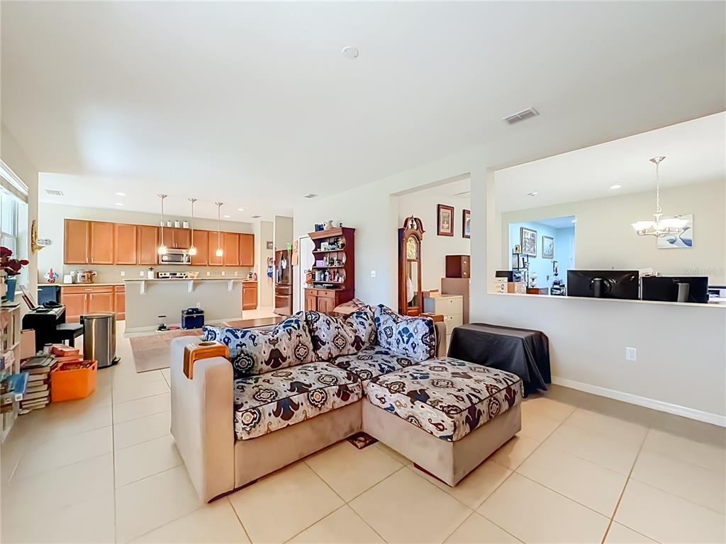A living room with a patterned sectional sofa opens to a kitchen with wood cabinets — 11913 VERRAZANO DRIVE, ORLANDO, FL