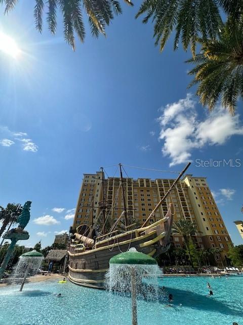 A large pirate ship structure sits in a swimming pool in front of a tall hotel — 8101 RESORT VILLAGE DRIVE UNIT 3608, ORLANDO, FL