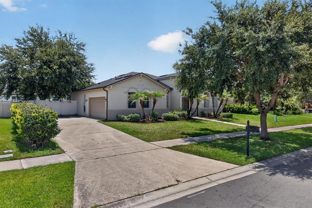 A single-story house with a beige exterior, a concrete driveway, and mature trees in front — 3922 CEDAR HAMMOCK TRAIL, ST CLOUD, FL