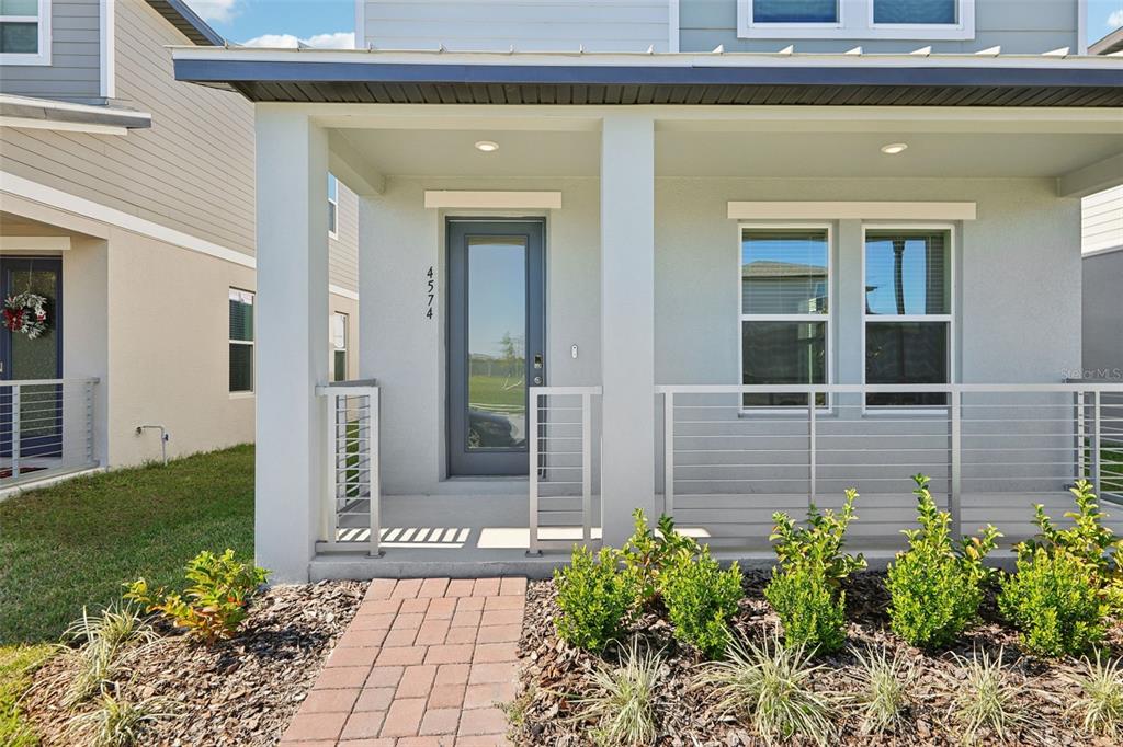 A front porch with a gray door, metal railings, and a brick walkway — 4574 HOMESTEAD TRAIL, ST CLOUD, FL