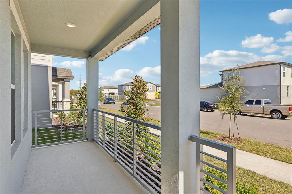 A covered balcony with metal railings overlooks a suburban street with houses and parked cars — 4574 HOMESTEAD TRAIL, ST CLOUD, FL