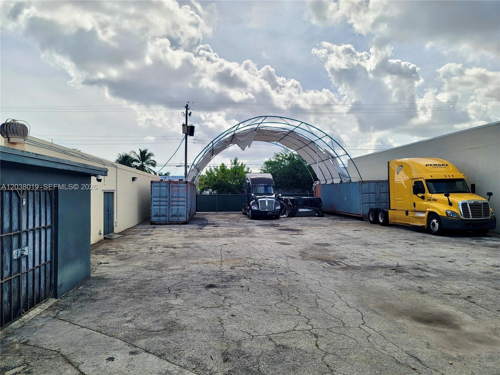 An outdoor storage lot features two semi-trucks, shipping containers, and a large arched canopy structure — 2216 N 20th Ave, Hollywood FL 33020, HOLLYWOOD, FL