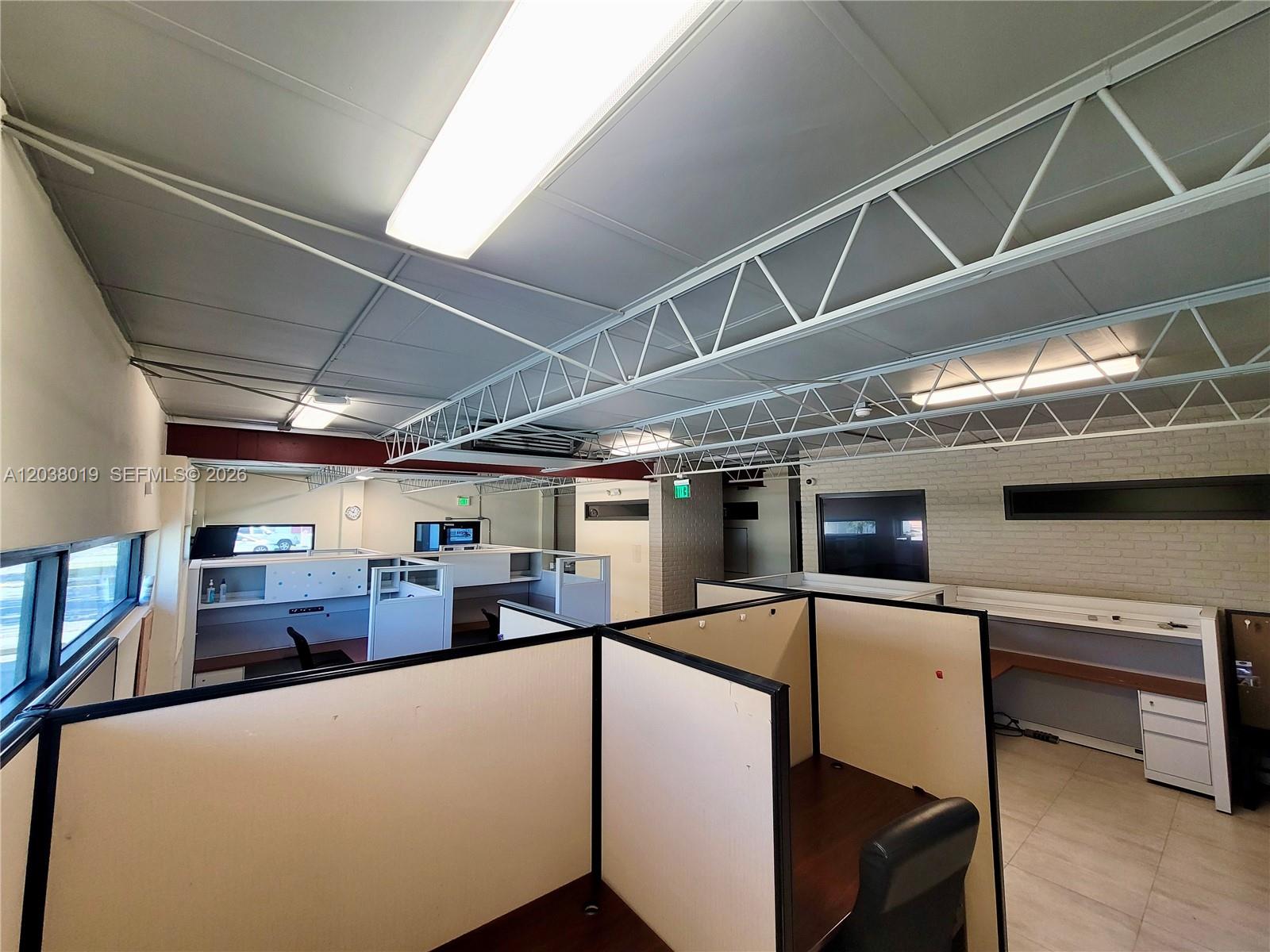 An office space features cubicle workstations, exposed ceiling trusses, and a brick accent wall — 2216 N 20th Ave, Hollywood FL 33020, HOLLYWOOD, FL