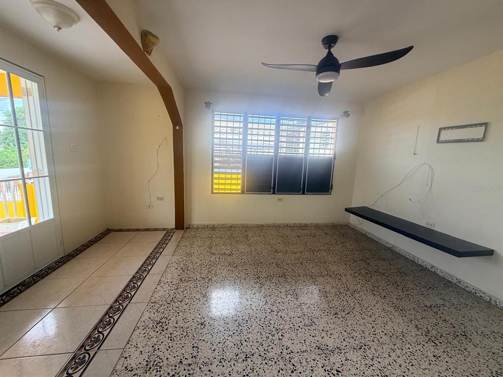 An empty living room features a ceiling fan, a floating shelf, and speckled tile flooring — Carr. 411, Km. 0.2 LOS POZOS, SECTOR CALVACHE, RINCON, PR