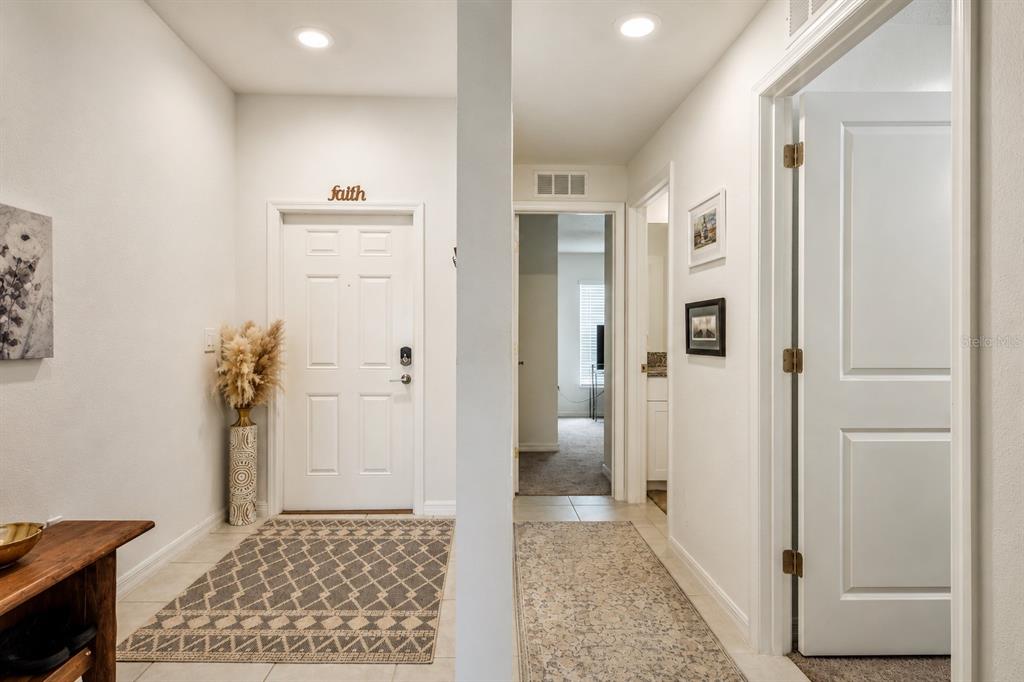 An entryway features a white front door, tiled floors, and a hallway leading to rooms — 13191 GARNET RASPBERRY AVENUE, WIMAUMA, FL