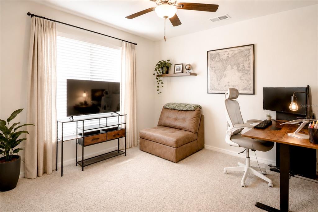 A home office features a desk, a brown armless chair, a television, and a map — 13191 GARNET RASPBERRY AVENUE, WIMAUMA, FL