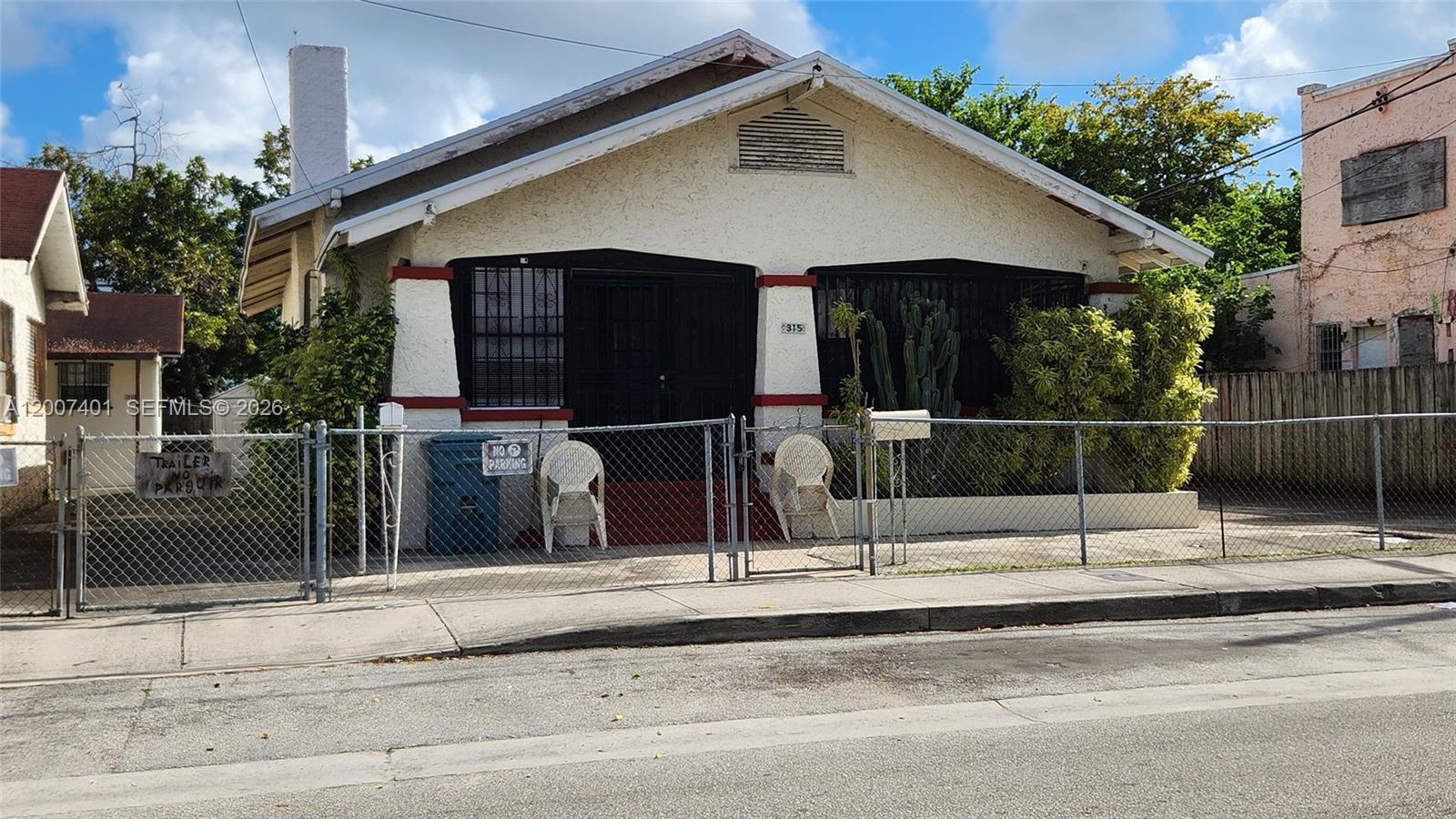 A single-story house with a white stucco facade, a chain-link fence, and a front porch — 315 SW 10th Ave, Miami FL 33130, MIAMI, FL