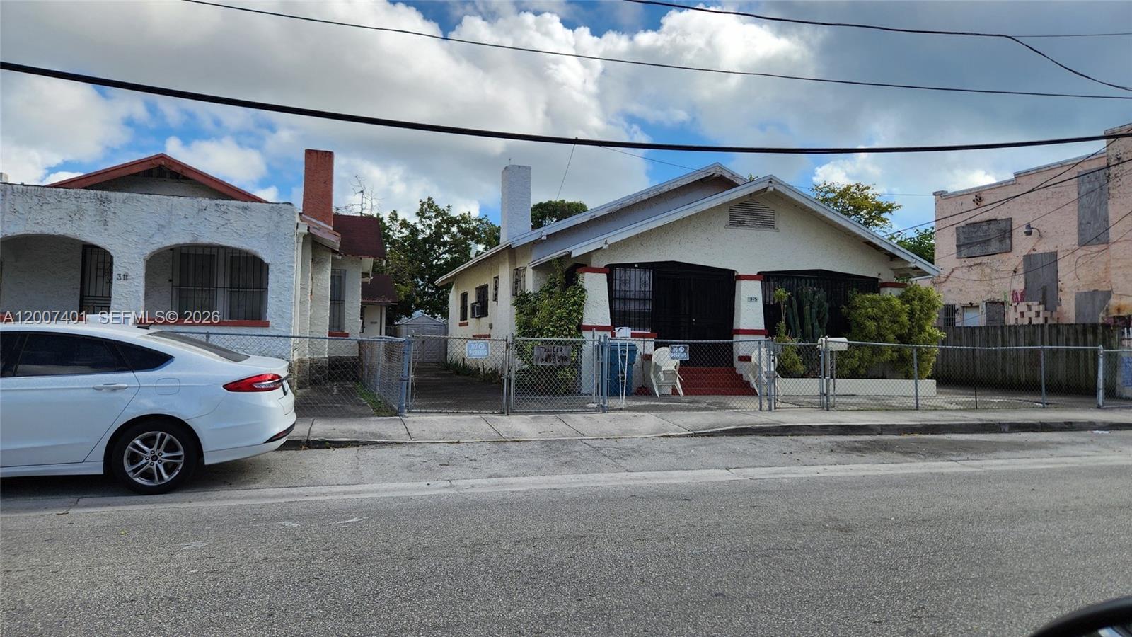 A white single-story house with a fenced front yard sits beside a neighboring residence — 315 SW 10th Ave, Miami FL 33130, MIAMI, FL