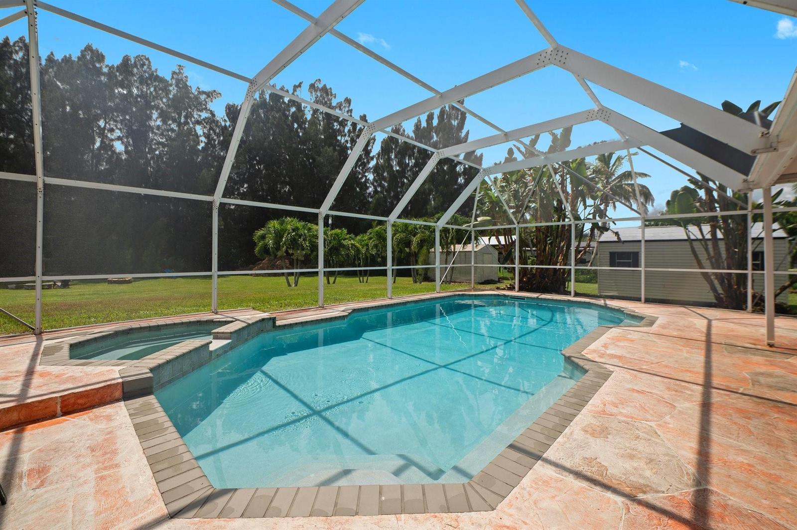A screened-in swimming pool and spa with a stone patio and a large backyard — 5191 SW 188th Avenue, Southwest Ranches FL 33332, SOUTHWEST RANCHES, FL