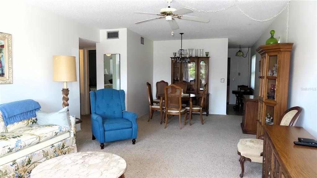 A living and dining area features carpeted floors, a blue armchair, and a wooden hutch — 2457 ECUADORIAN WAY UNIT 85, CLEARWATER, FL