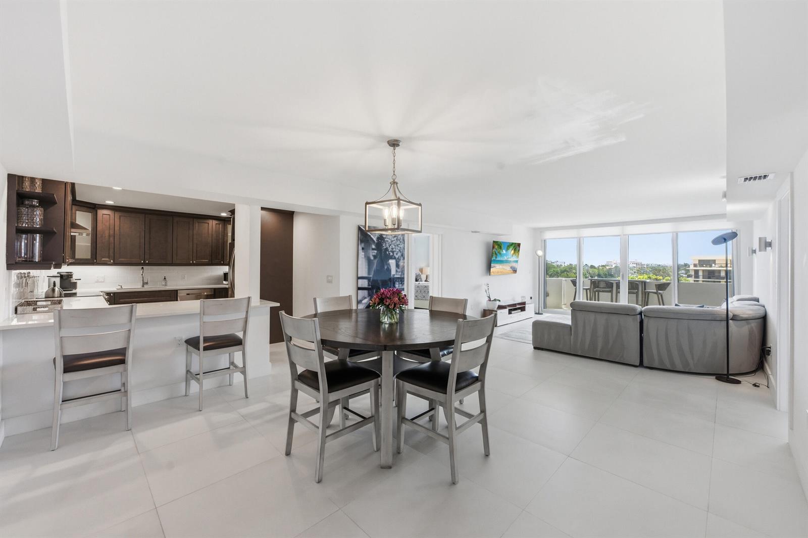 An open-concept living and dining area features white tile floors, dark cabinetry, and balcony views — 2773 S Ocean Boulevard # 5140, Palm Beach FL 33480, PALM BEACH, FL