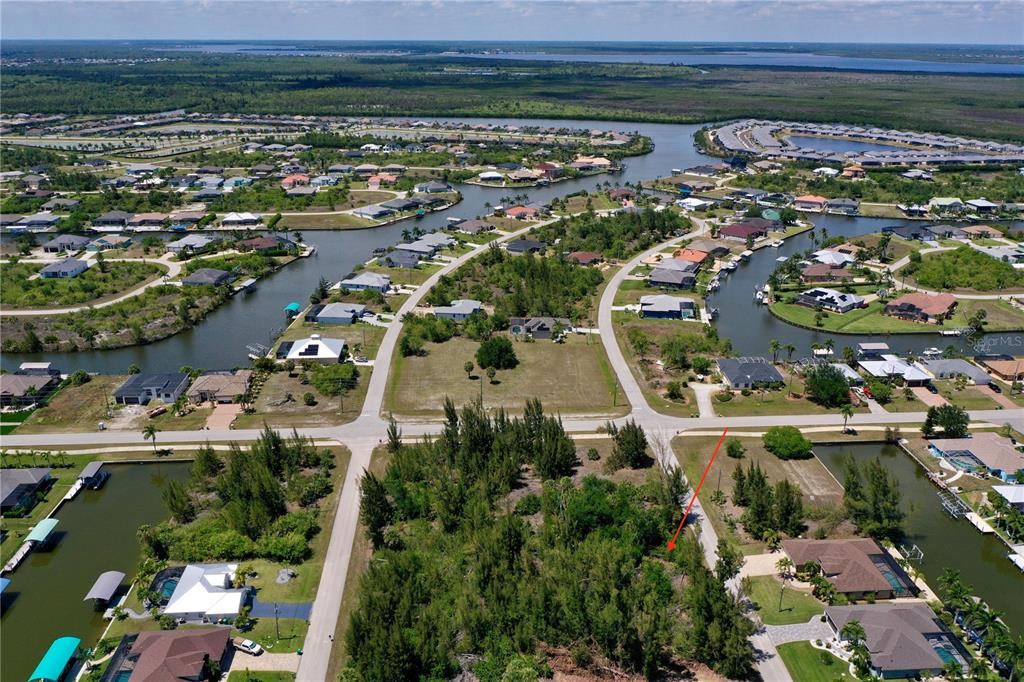 An aerial view shows a vacant residential lot surrounded by houses and canals — 8401 ANTWERP CIRCLE, PORT CHARLOTTE, FL