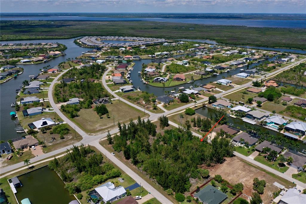 An aerial view shows a vacant, tree-covered residential lot in a canal-front community — 8401 ANTWERP CIRCLE, PORT CHARLOTTE, FL