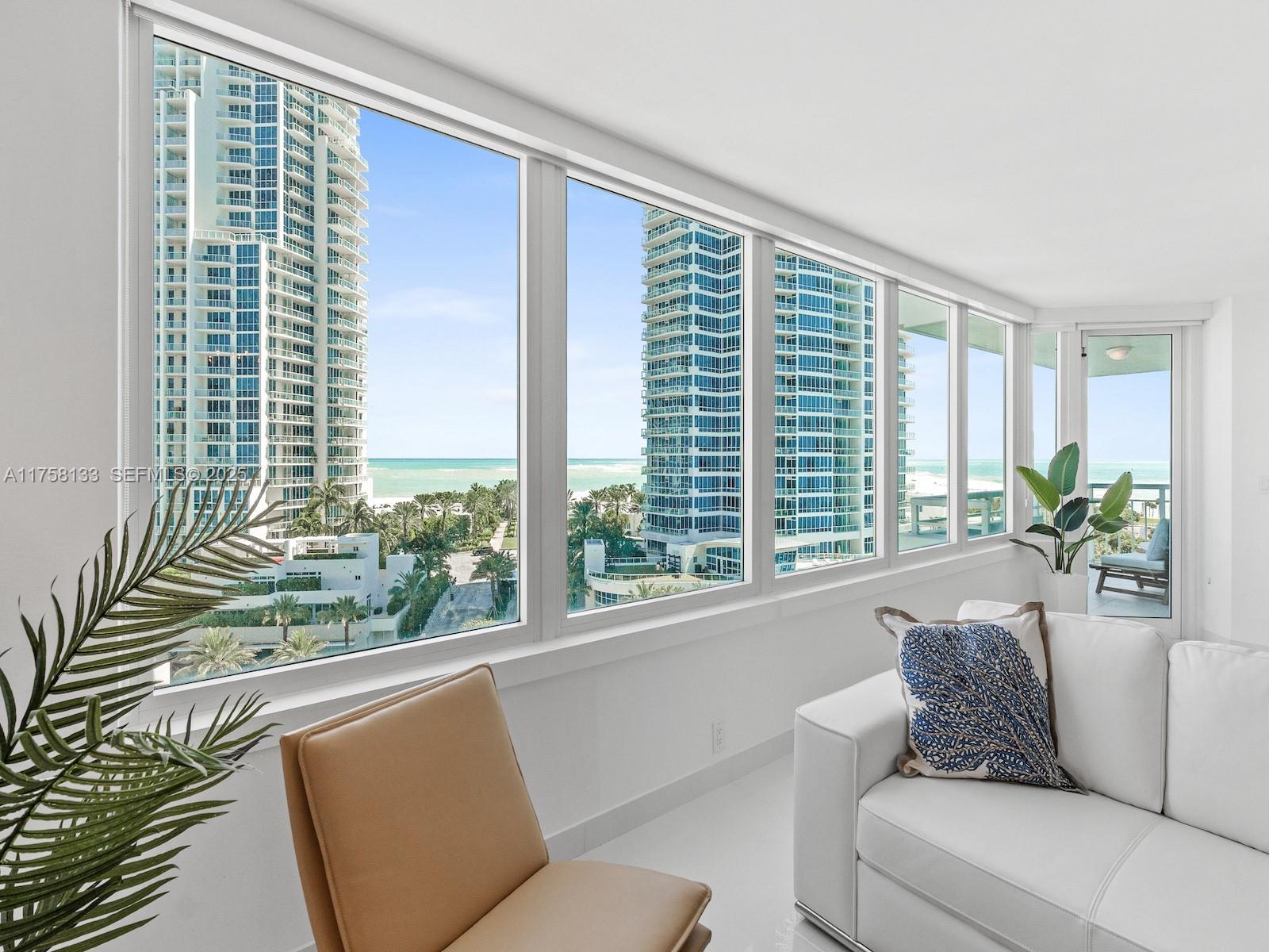 A bright living room features floor-to-ceiling windows overlooking high-rise buildings and the ocean — 400 S Pointe Dr # 906, Miami Beach FL 33139, MIAMI BEACH, FL