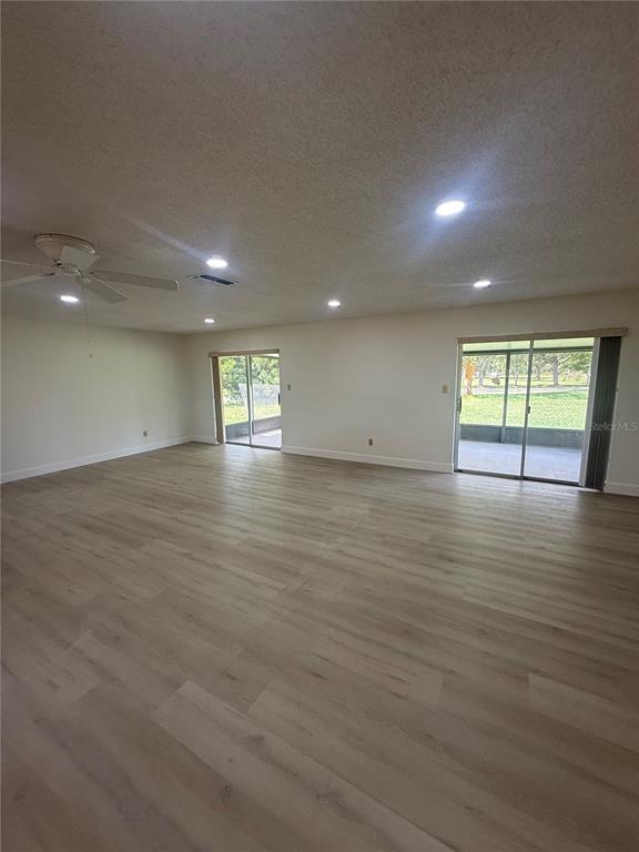 A spacious room features light wood-look flooring, recessed lighting, a ceiling fan, and sliding doors — 10719 LAZY LAKE DRIVE, ORLANDO, FL