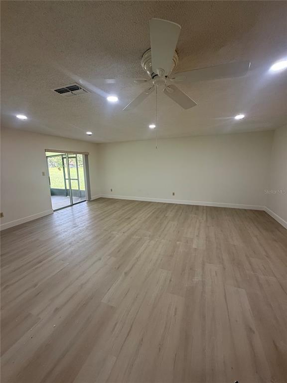 An empty room with light wood-look flooring, a ceiling fan, recessed lighting, and sliding doors — 10719 LAZY LAKE DRIVE, ORLANDO, FL