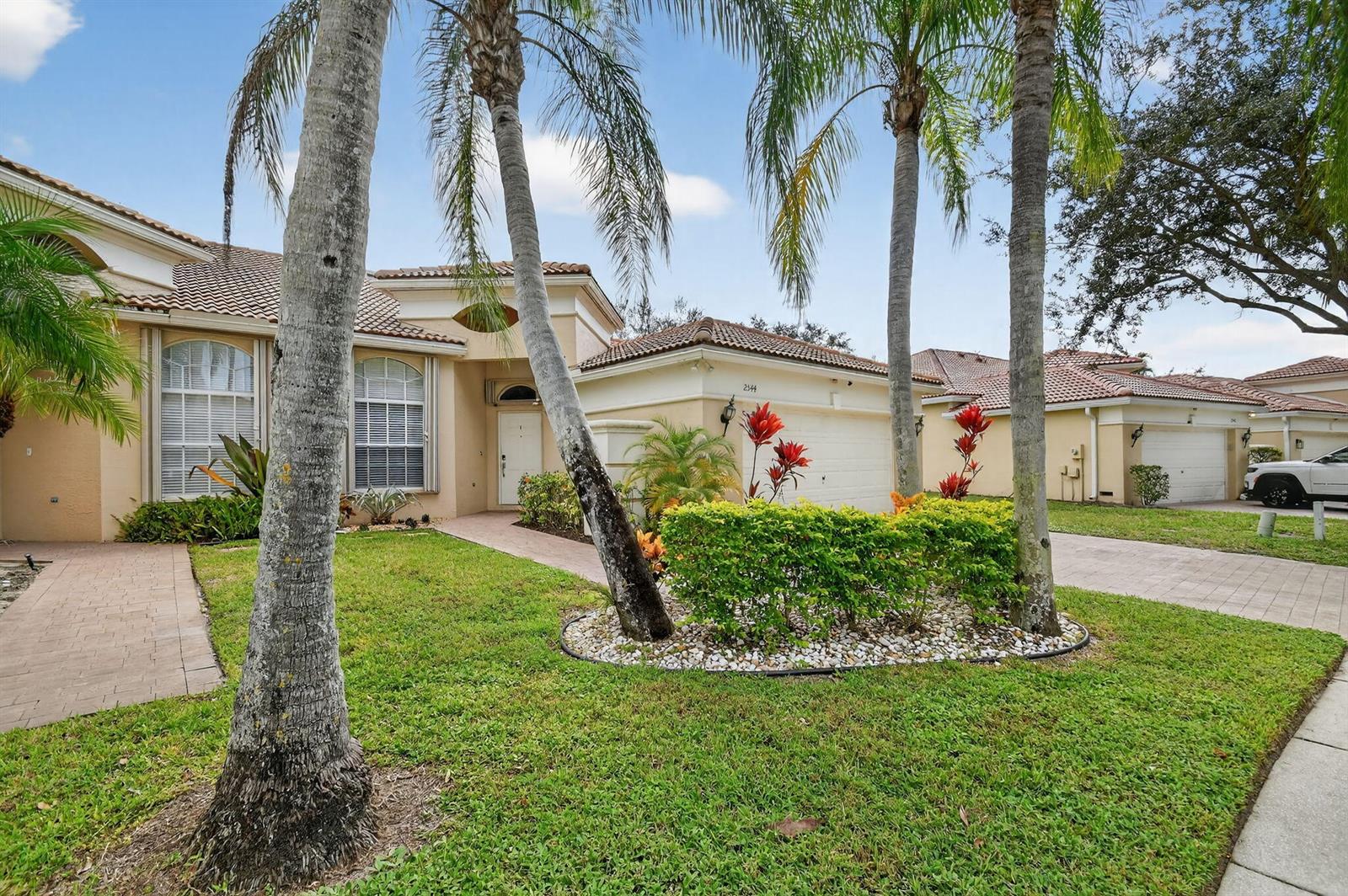 A single-story house with a tiled roof, palm trees, and a landscaped front yard — 2544 Sandy Cay, West Palm Beach FL 33411, WEST PALM BEACH, FL