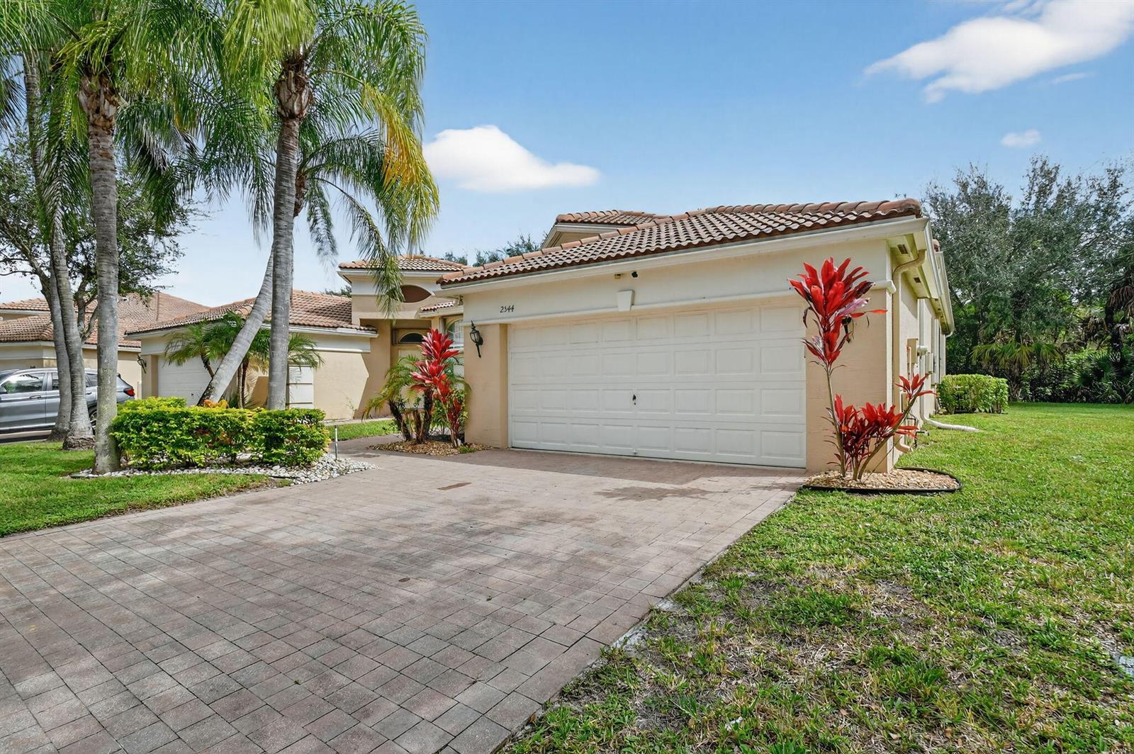 A single-story house with a tiled roof, a two-car garage, and a paved driveway — 2544 Sandy Cay, West Palm Beach FL 33411, WEST PALM BEACH, FL