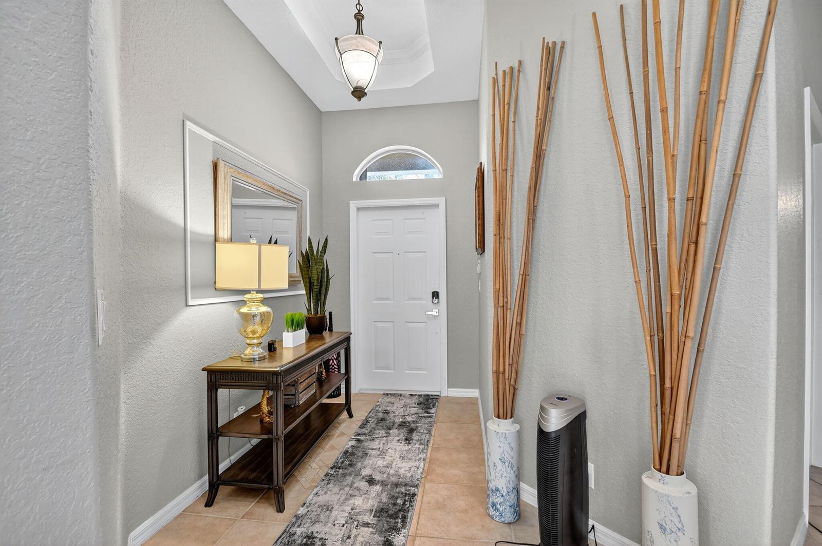 An entryway features a console table, a runner rug, and tall decorative bamboo stalks — 2544 Sandy Cay, West Palm Beach FL 33411, WEST PALM BEACH, FL