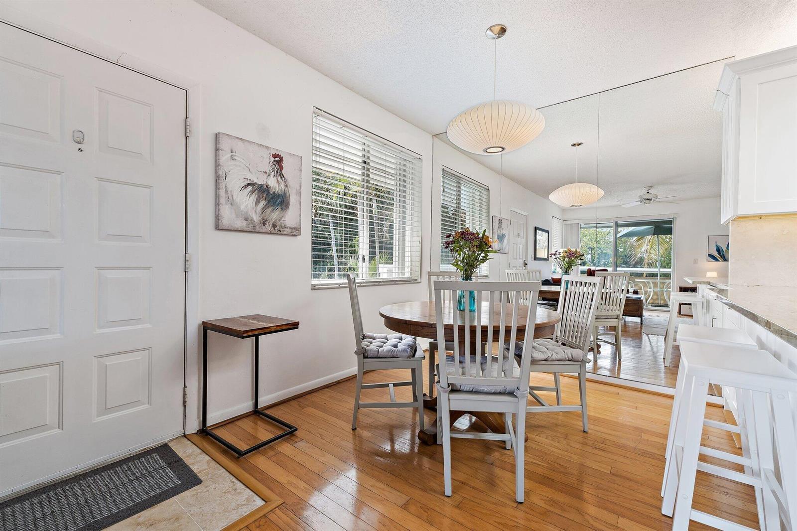 A dining area with a round wooden table, white chairs, and a large wall mirror — 353 S Us Hwy 1 # C7, Jupiter FL 33477, JUPITER, FL