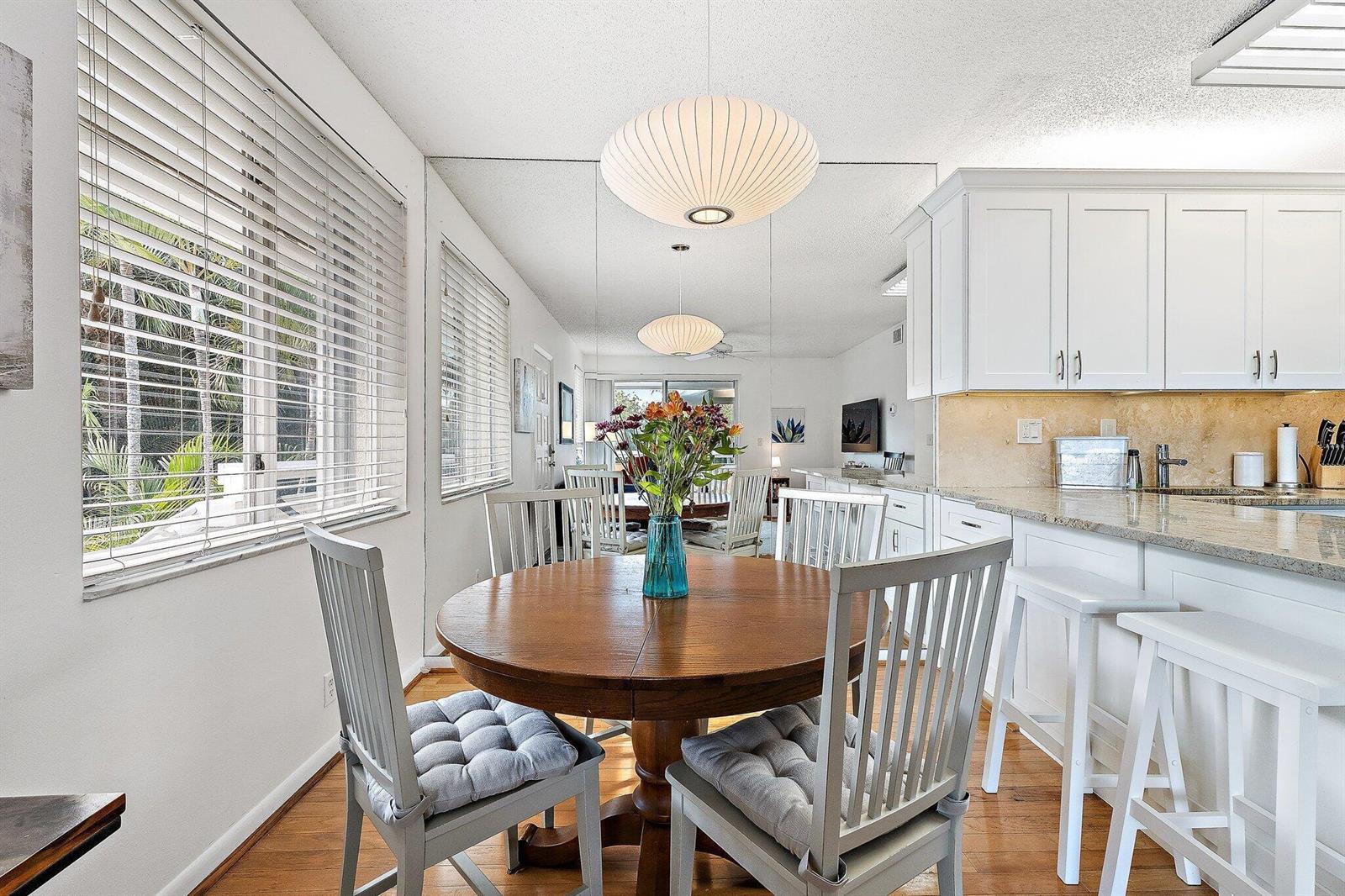 A dining area with a round wooden table and chairs sits beside a white kitchen — 353 S Us Hwy 1 # C7, Jupiter FL 33477, JUPITER, FL