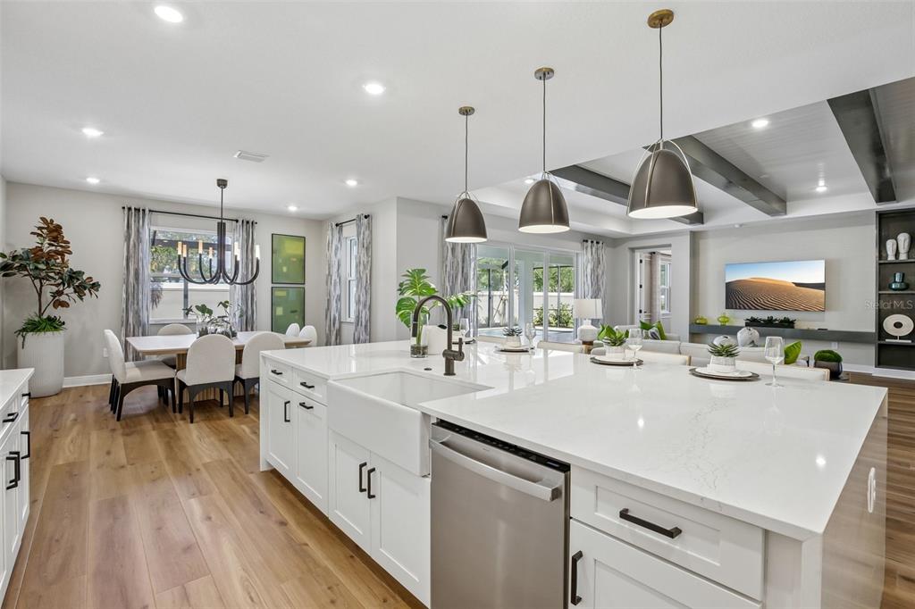 A modern kitchen features a large white quartz island, farmhouse sink, and stainless steel appliances — 8924 DEEP HORIZON LOOP, PARRISH, FL