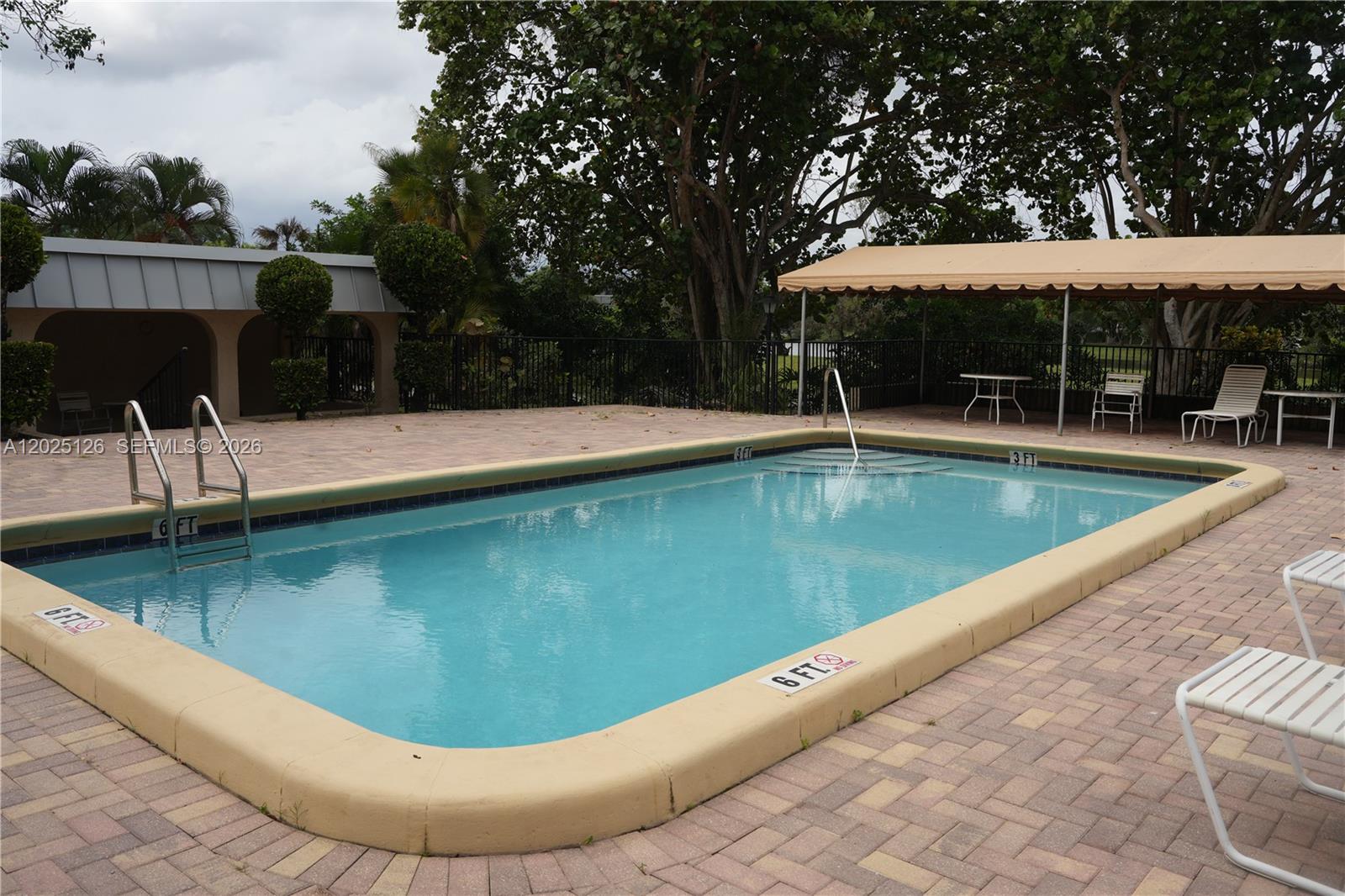 An outdoor swimming pool with a tan coping edge sits on a brick patio — 6001 N Falls Cir Dr # 203, Lauderhill FL 33319, LAUDERHILL, FL
