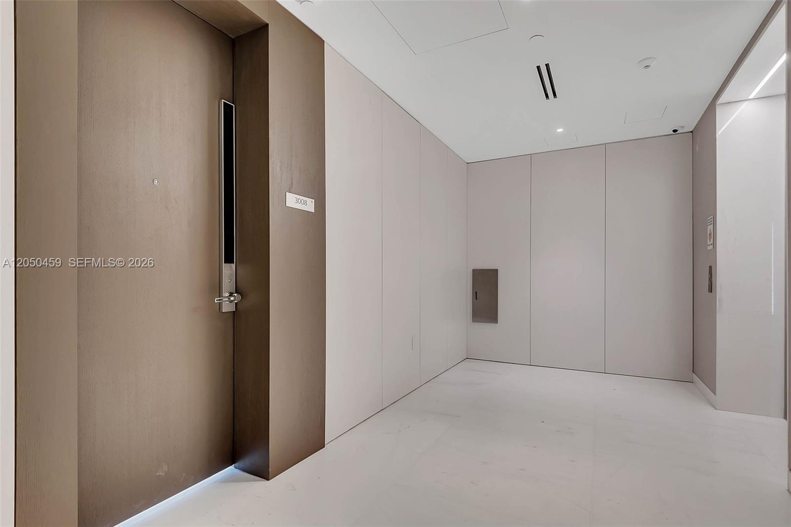 A hallway features a brown door labeled 3008, light-colored wall panels, and white flooring — 300 Biscayne Boulevard Way # 3008W, Miami FL 33131, MIAMI, FL