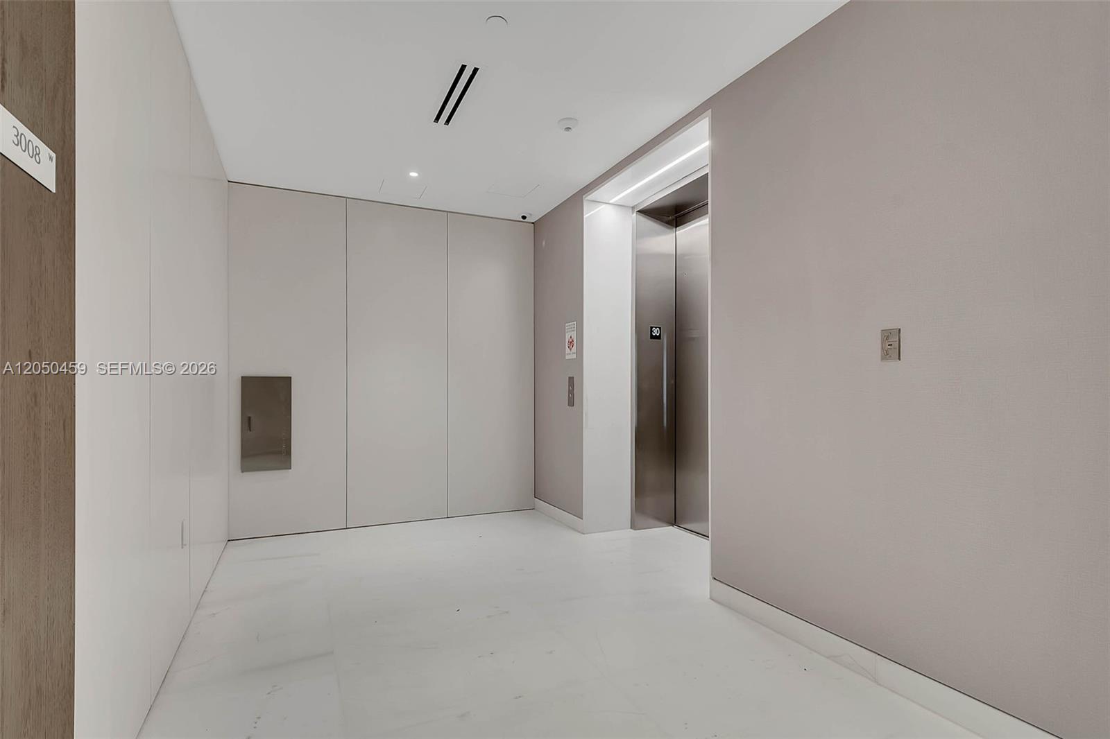 A modern elevator lobby features white marble floors, light-colored walls, and a stainless steel elevator — 300 Biscayne Boulevard Way # 3008W, Miami FL 33131, MIAMI, FL