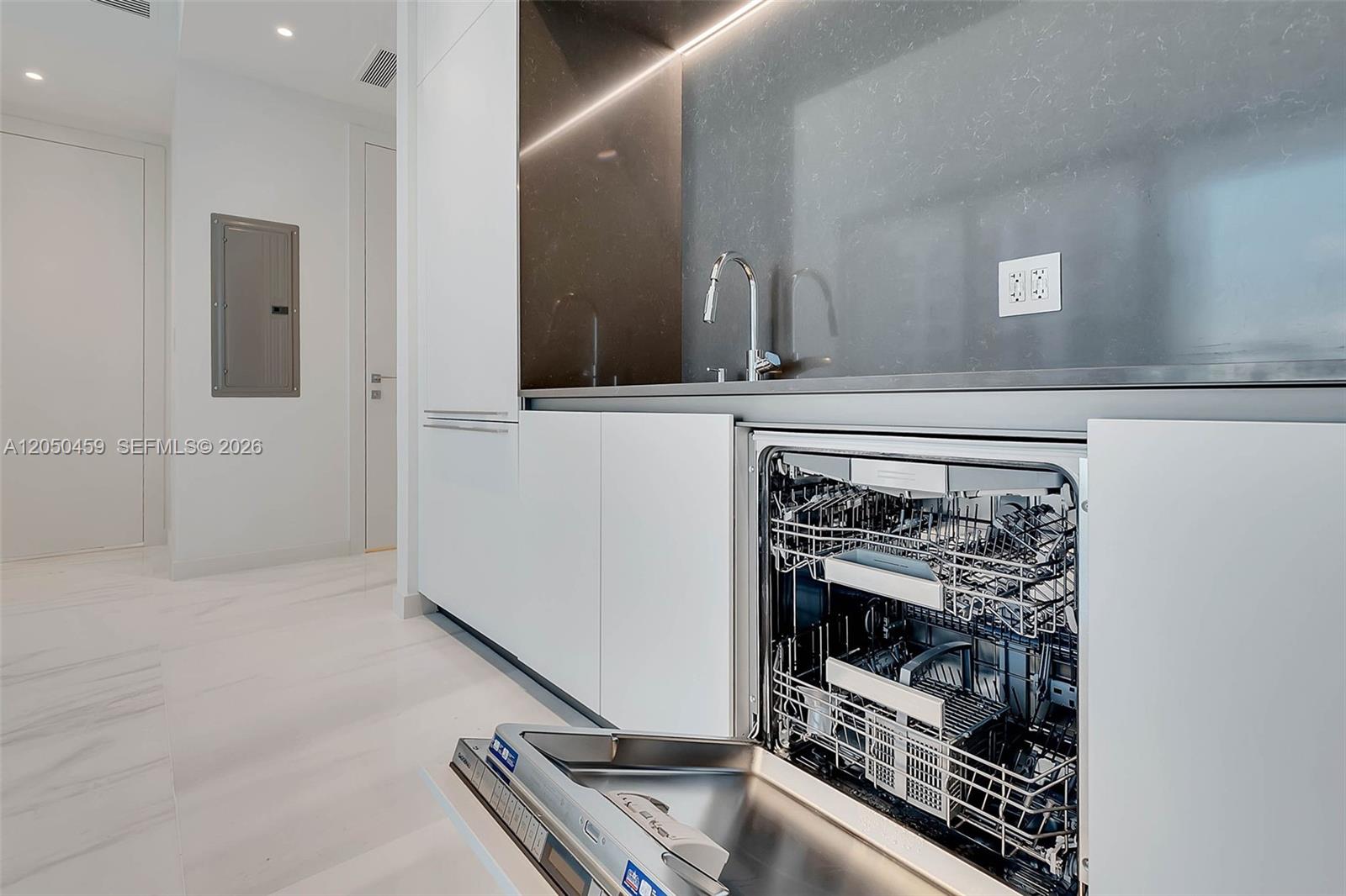 A modern kitchen features white cabinetry, a dark backsplash, and an open dishwasher — 300 Biscayne Boulevard Way # 3008W, Miami FL 33131, MIAMI, FL