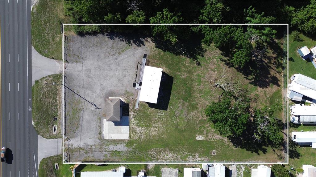This aerial view shows a rectangular lot containing two small buildings, gravel areas, and trees — 4109 US HIGHWAY 27 S, SEBRING, FL