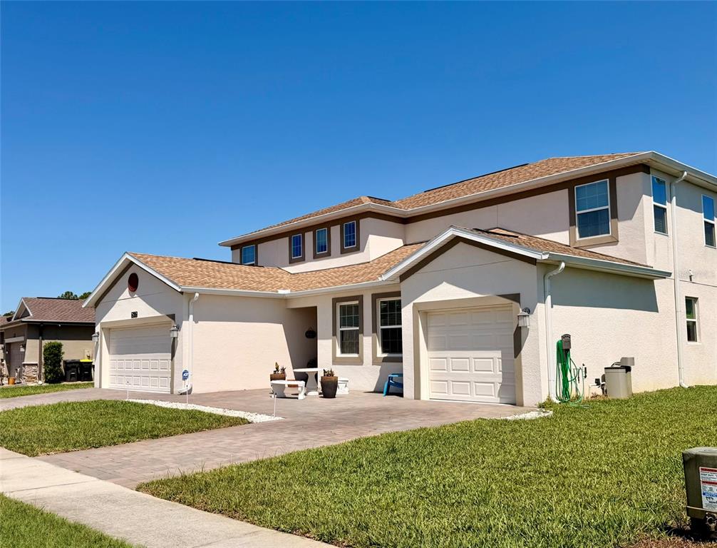 A two-story house with a beige stucco exterior, two garage doors, and a paved driveway — 2572 CAMDEN PARK CIRCLE, DAVENPORT, FL