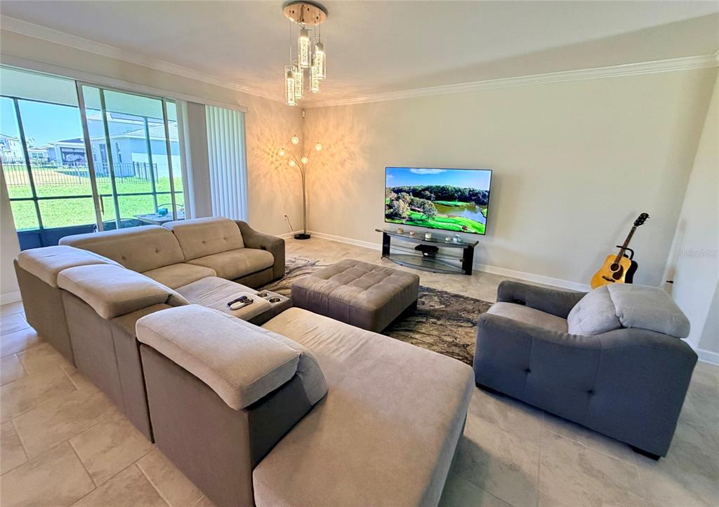 A living room features a large sectional sofa, a television, and a sliding glass door — 2572 CAMDEN PARK CIRCLE, DAVENPORT, FL
