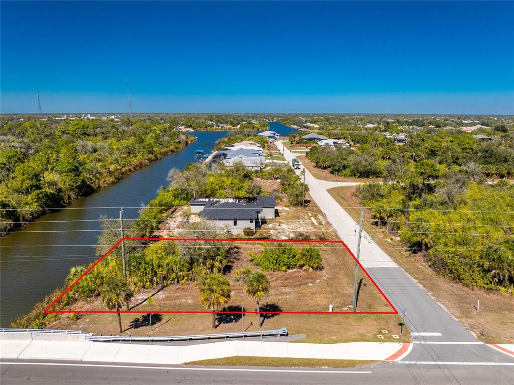 An aerial view shows a vacant, rectangular lot bordered by a road and a canal — 10311 REDONDO STREET, PORT CHARLOTTE, FL
